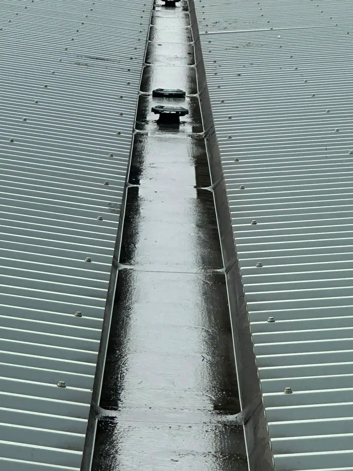 The same box gutter cleared back to bare metal with water running freely.