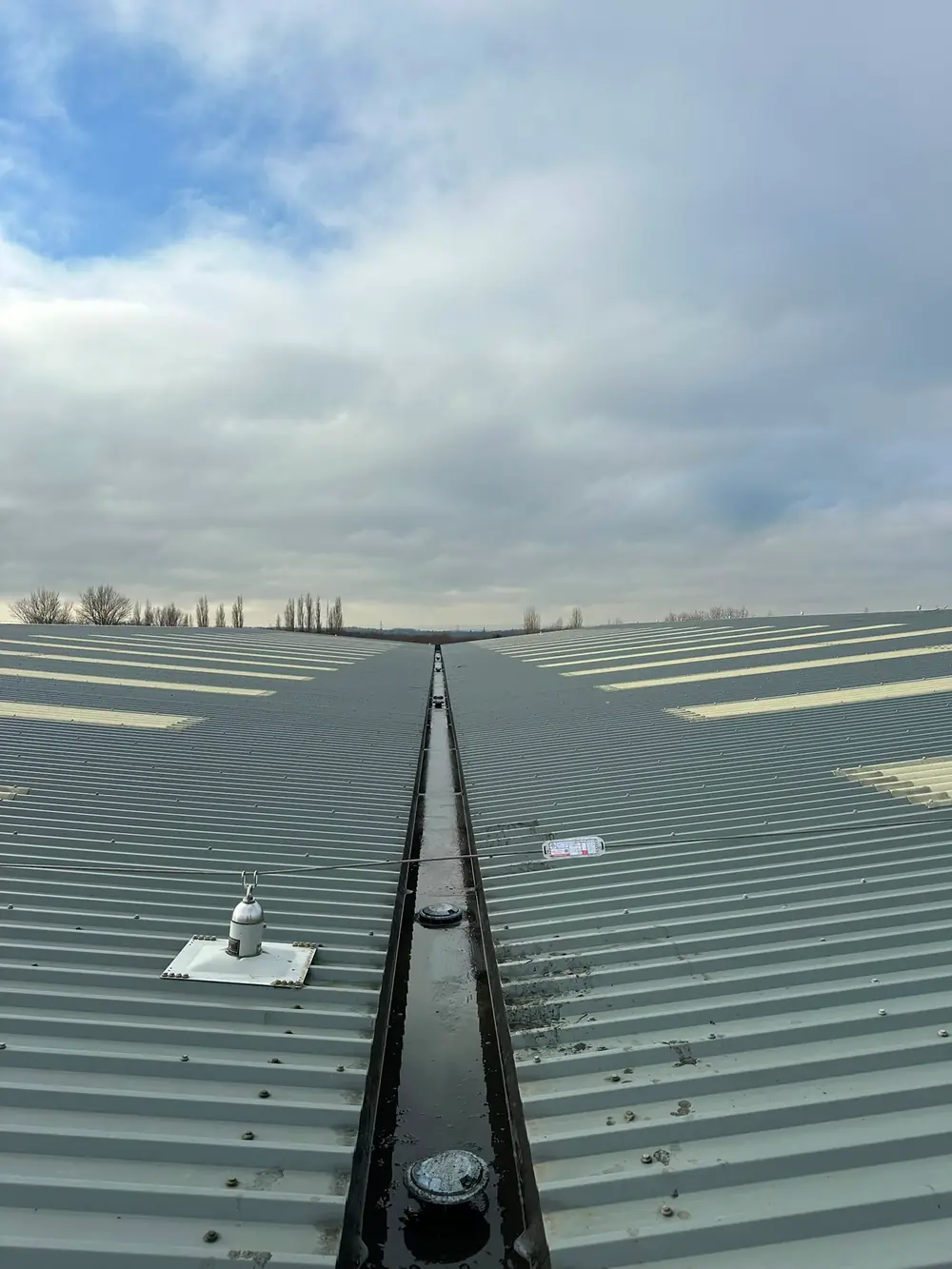 A wide view of an industrial roof and its valley gutter.
