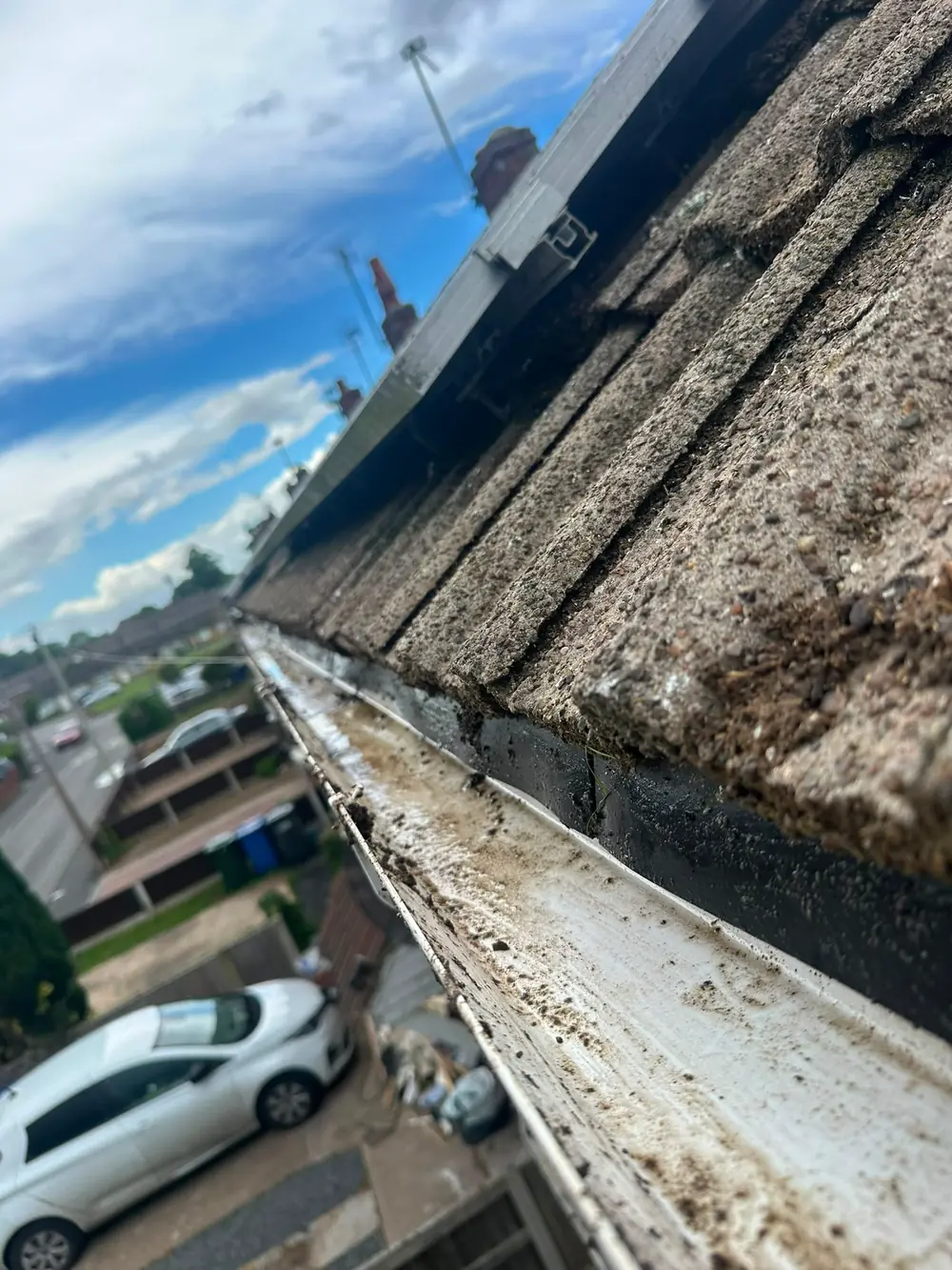 A silted white gutter photographed from roof level.