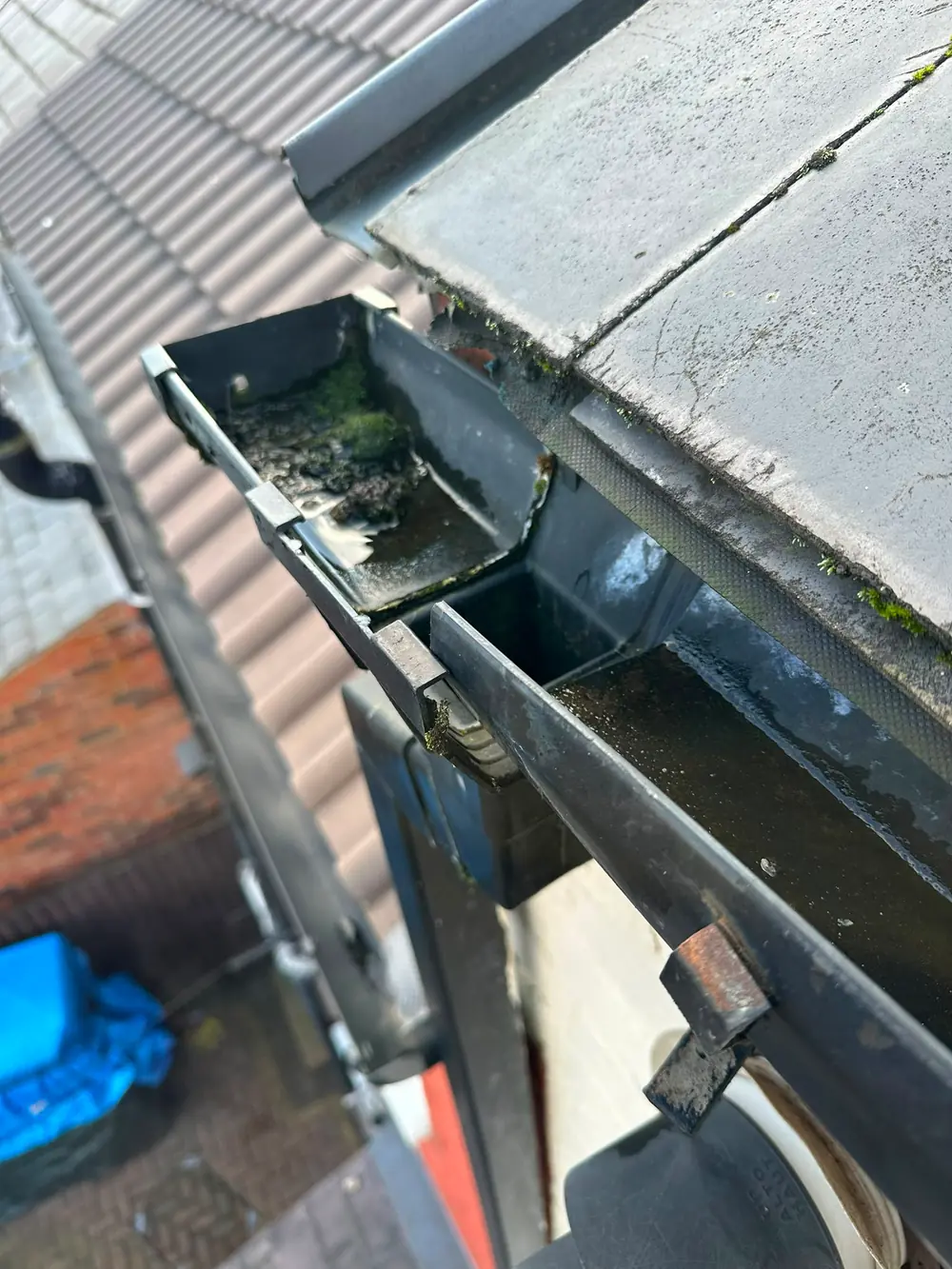 A gutter section lifted to show the debris behind it.