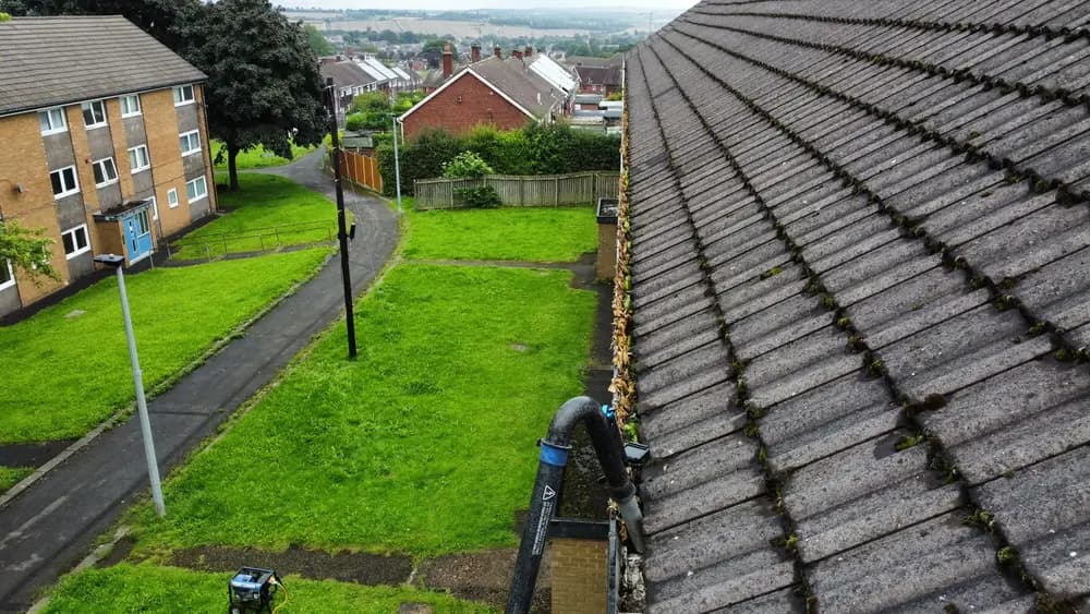 A leaf filled gutter run along a large roof.