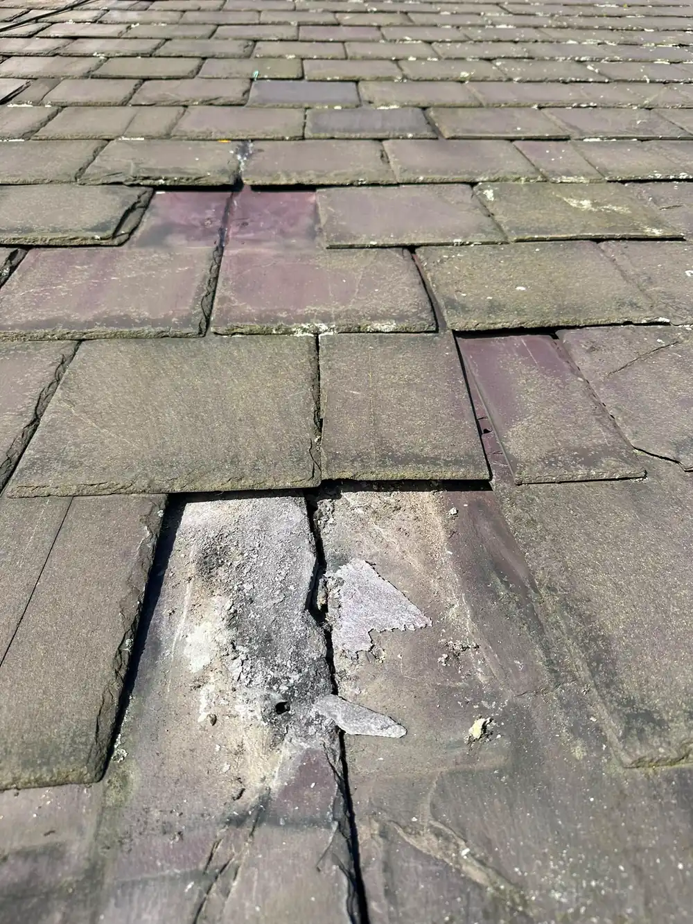 Slipped and cracked slates on an old roof.