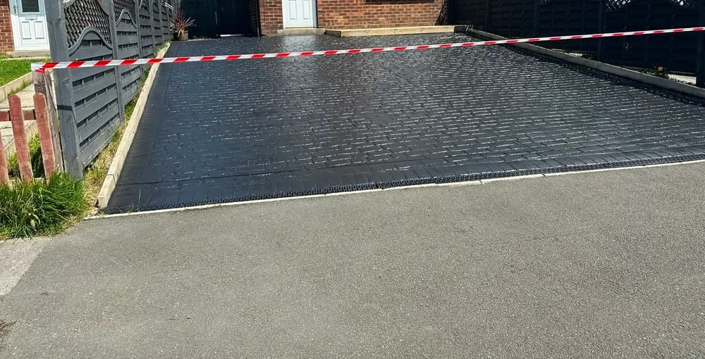 The same driveway after cleaning and resealing, deep black and still wet.