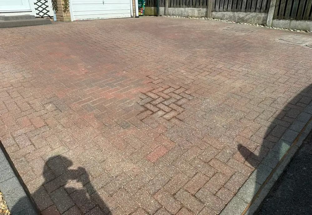 A dull, dirty red block paved driveway.