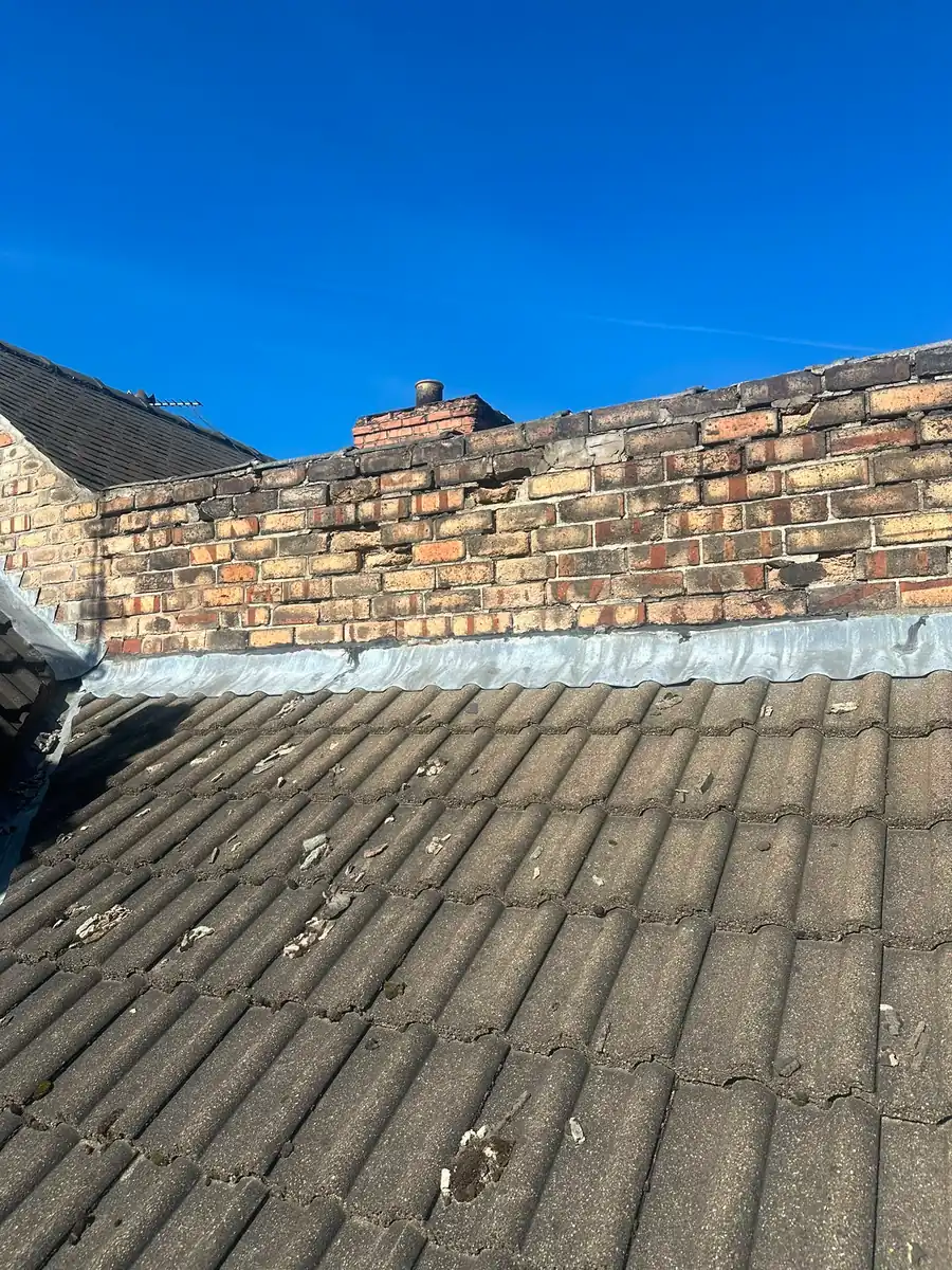 A chimney stack with fresh lead flashing and repointed brickwork.
