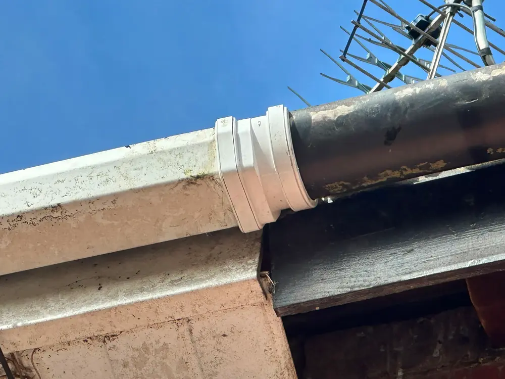 A new downpipe collar fitted into cast iron during gutter repairs.