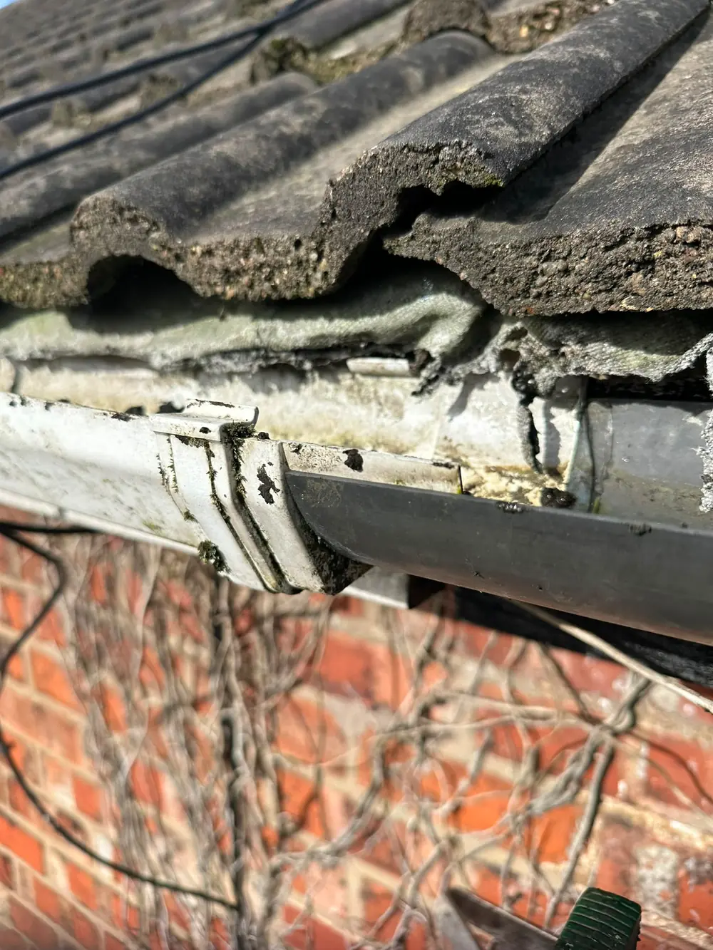 A failed gutter joint with rotted brackets behind it