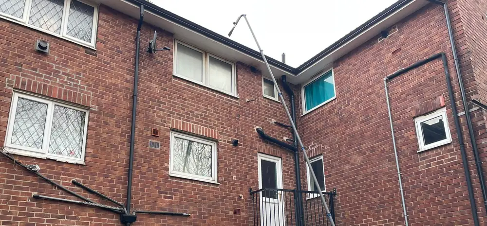 A high reach vacuum pole extended up to the third floor guttering of a block of flats.